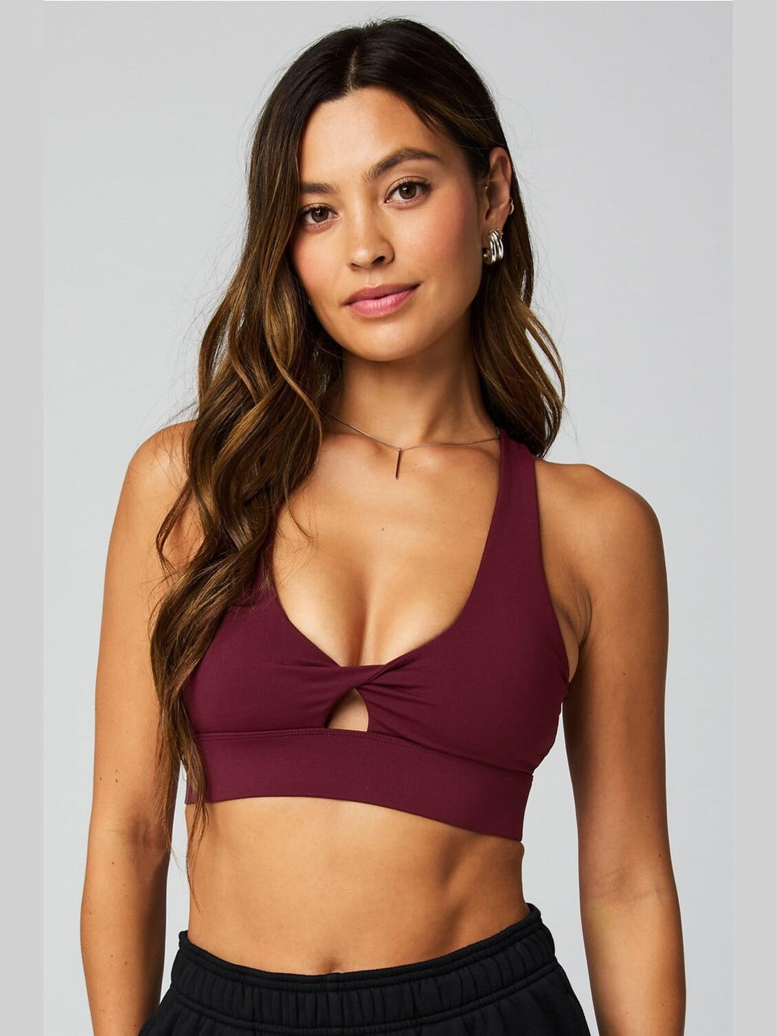 Deep burgundy Fabletics Oasis Twist sports bra with front keyhole cutout and crisscross straps for medium-impact support