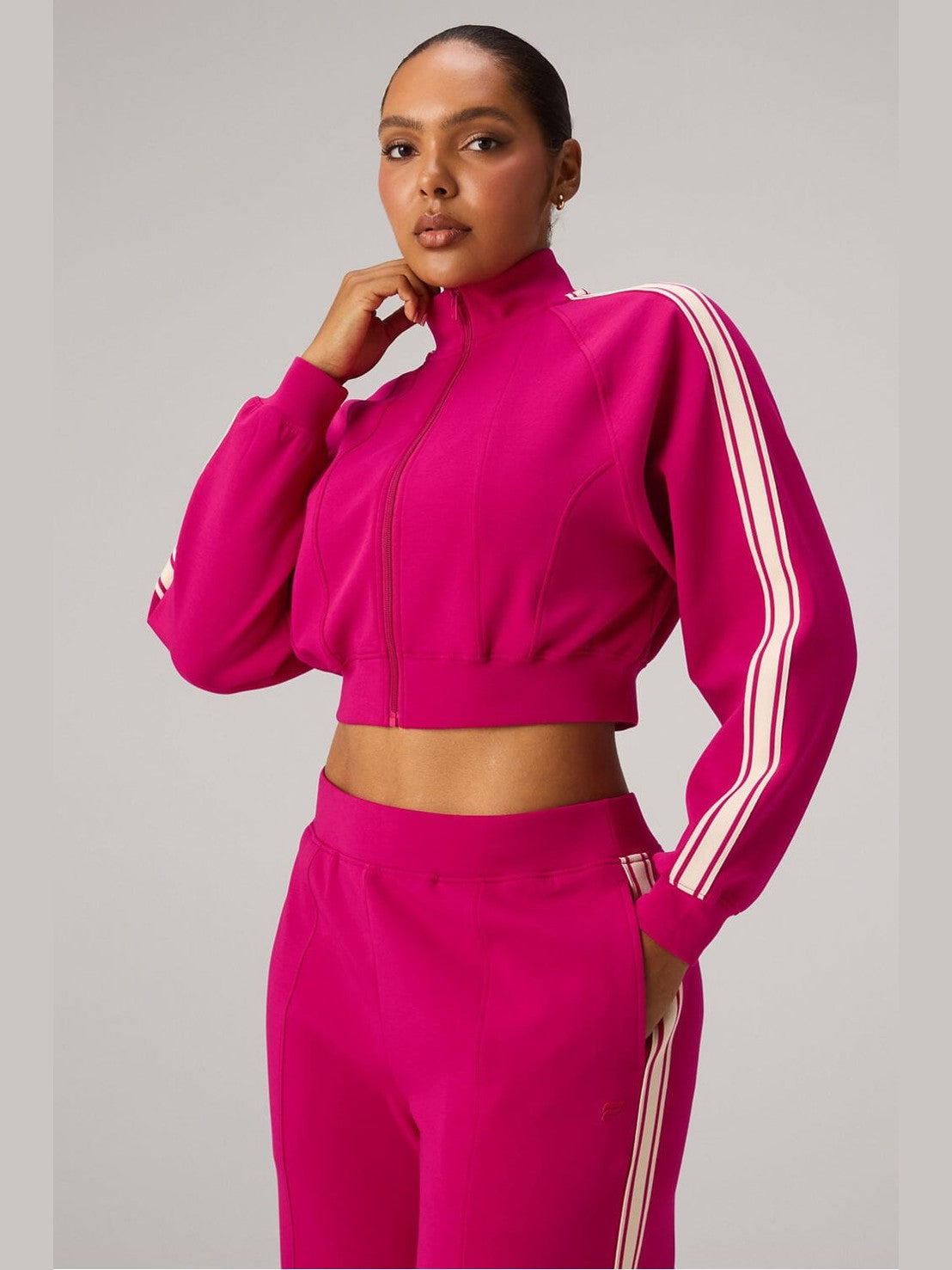 Fabletics fuchsia pink cropped full-zip track jacket with off-white sleeve stripes and mock neck