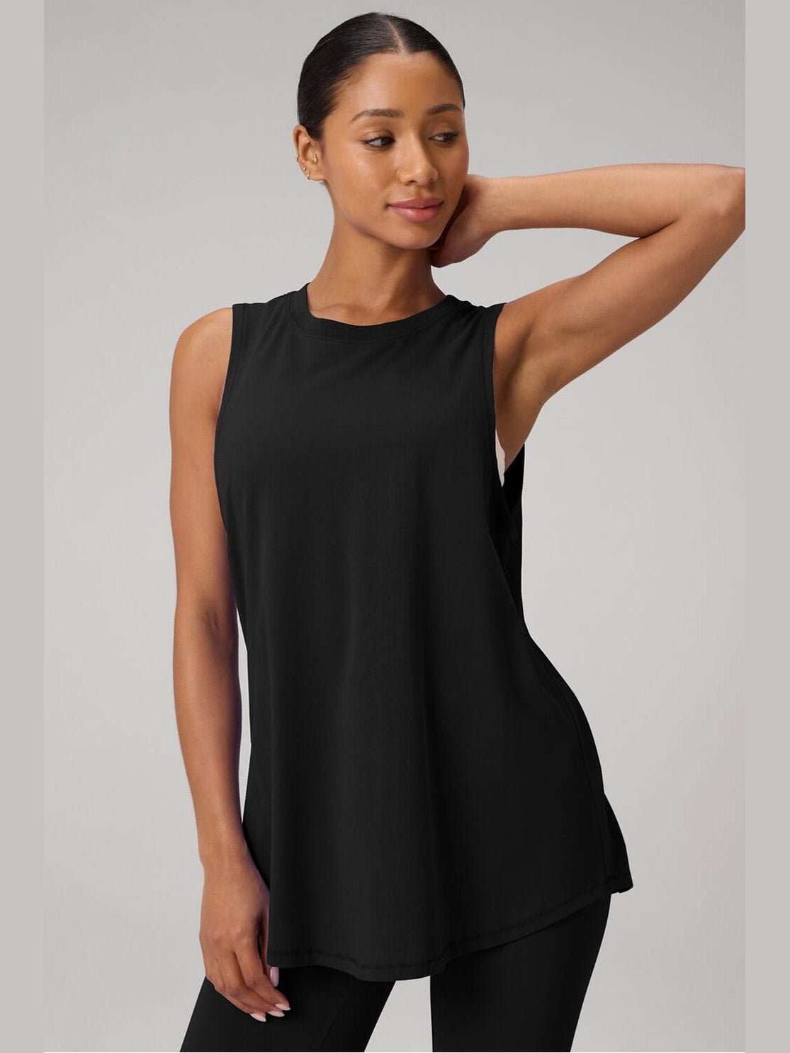 Fabletics black oversized muscle tank top with high-low hem and side slits, showcasing soft 100% cotton drape on model