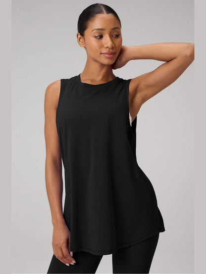 Fabletics black oversized muscle tank top with high-low hem and side slits, showcasing soft 100% cotton drape on model